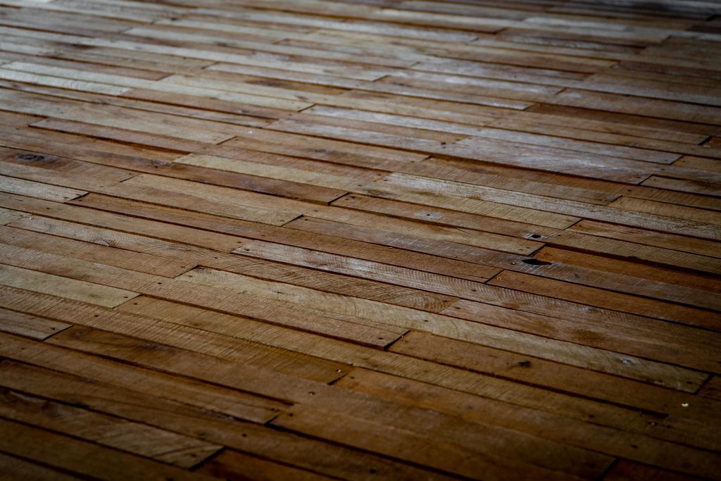 Detailed view of rustic wooden floor with staggered planks showcasing natural texture. Vue détaillée d'un plancher en bois rustique avec des planches décalées mettant en évidence la texture naturelle.