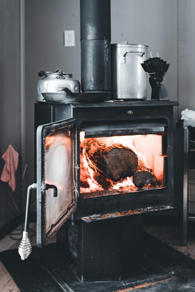 A warm wood-burning stove adds a cozy touch to an indoor space, perfect for cold seasons. Un poêle à bois chaud ajoute une touche confortable à un espace intérieur, parfait pour les saisons froides.