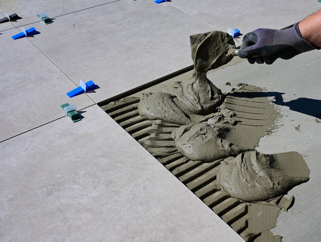 Main gantée appliquant mortier pour carrelage