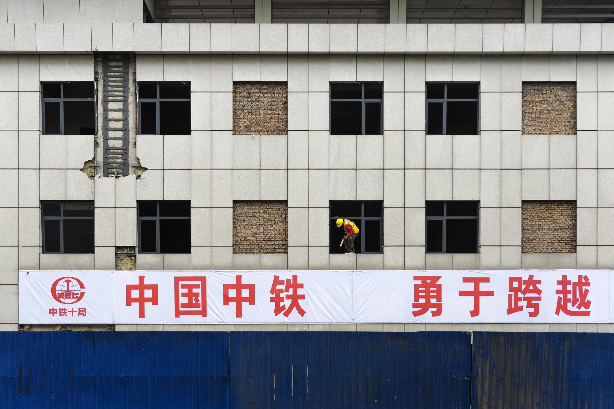 Travailleur posant bâche sur façade de construction