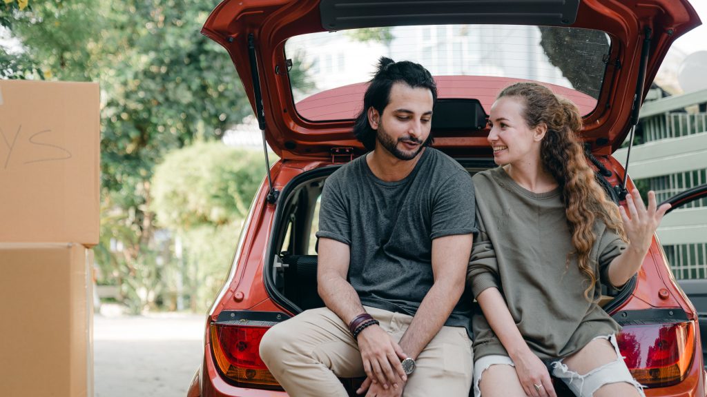 Couple multiracial joyeux déchargeant cartons de voiture