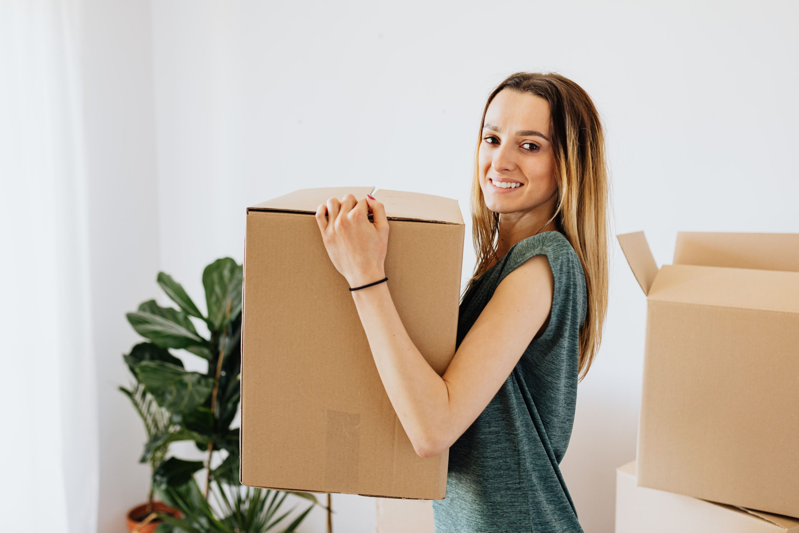 Femme souriante portant carton déménagement maison