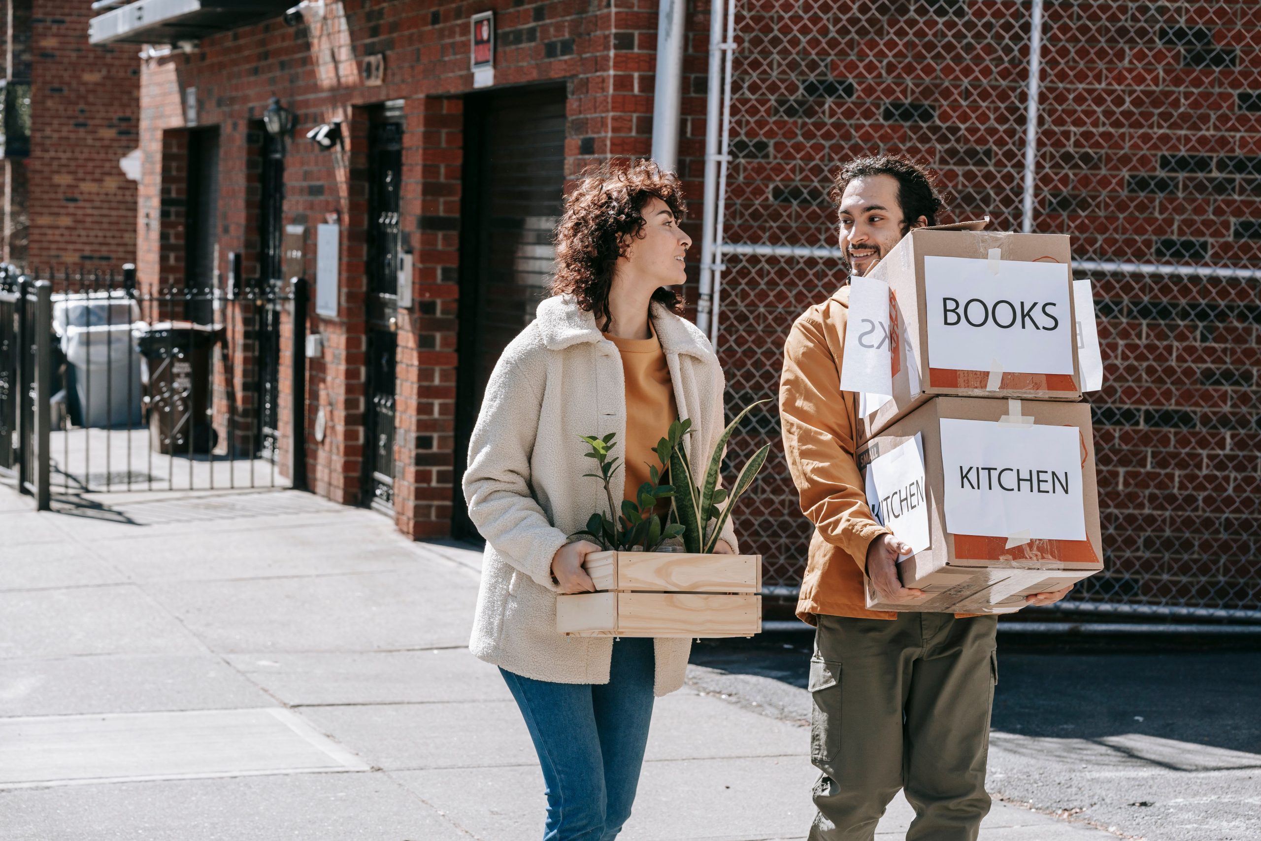 Couple heureux déménageant avec plantes et cartons