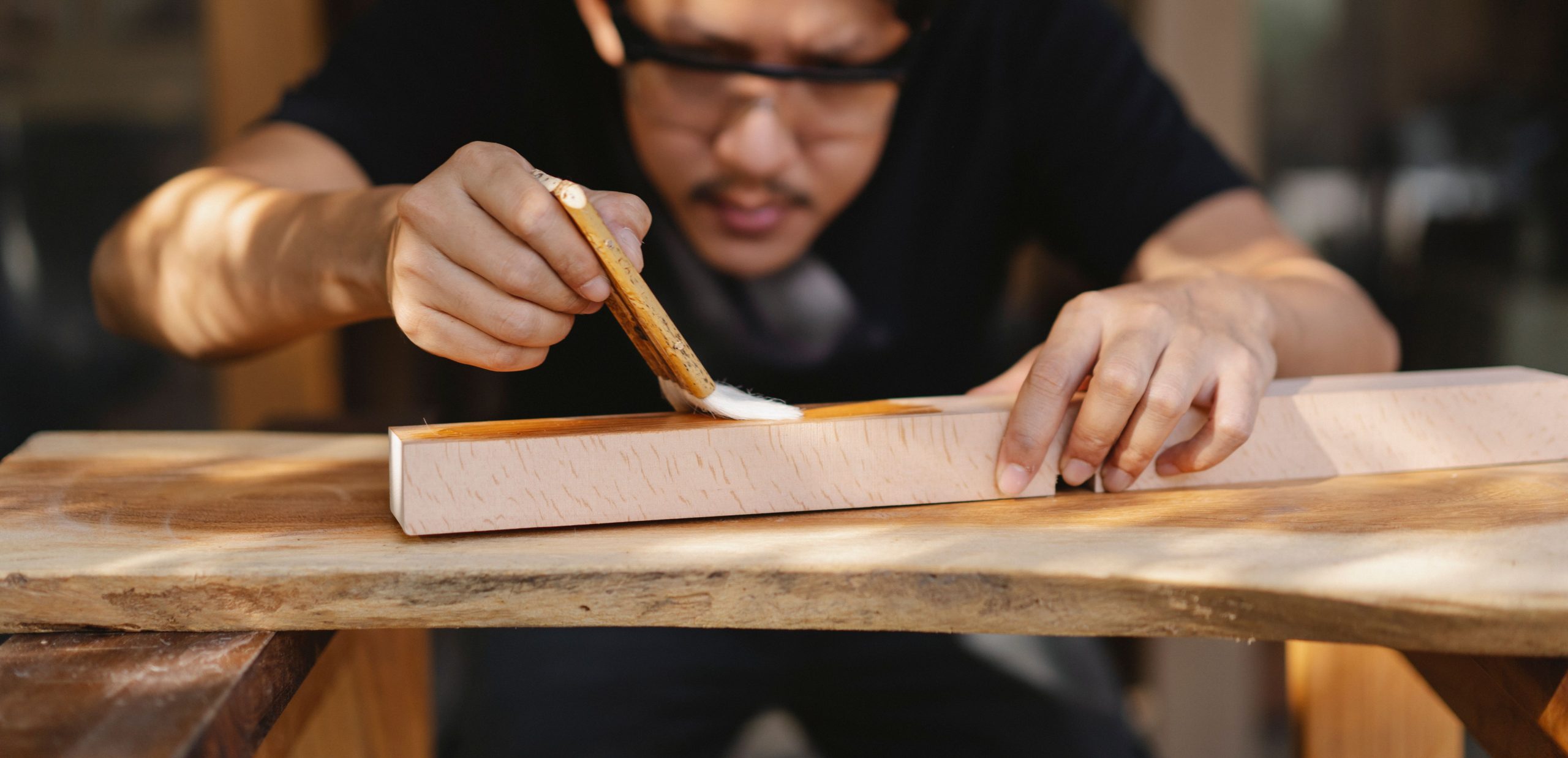 Artisan appliquant du vernis sur une planche en bois